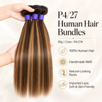 Hands holding three bundles of silky straight P4/27 piano highlight human hair showing luster and softness